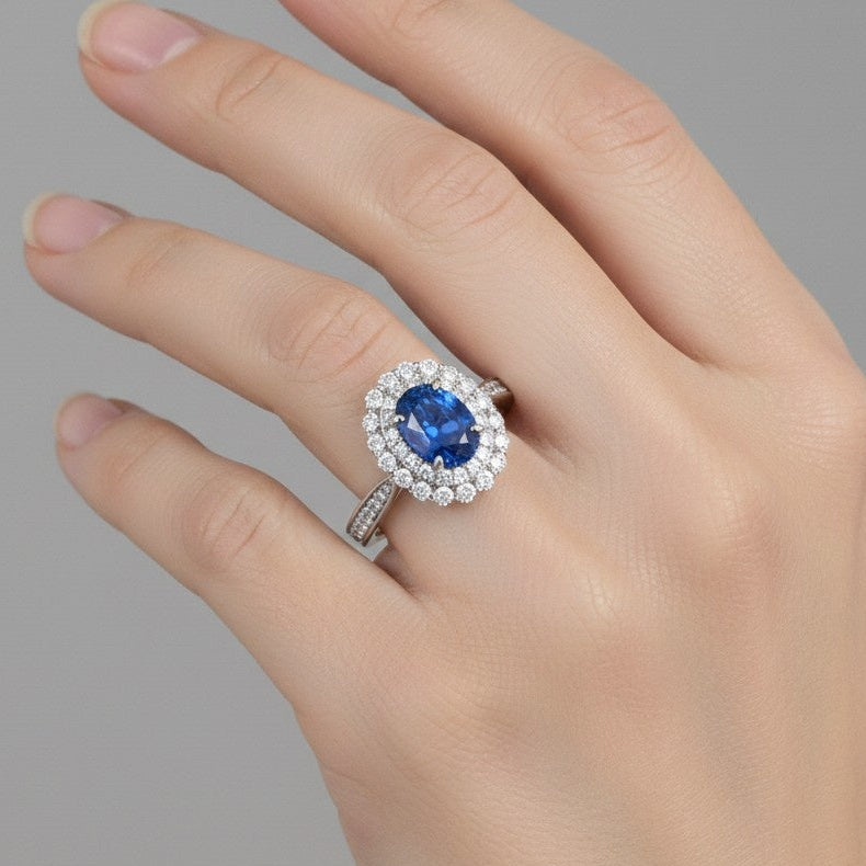 Hand wearing a 925 silver ring with a blue gemstone on a gray background