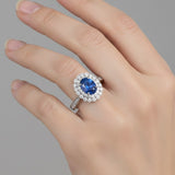 Hand wearing a 925 silver ring with a blue gemstone on a gray background
